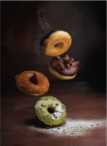 Several donuts falling onto a table.