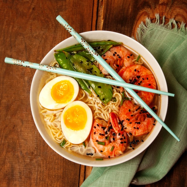 A bowl of spicy shrimp ramen with chop sticks laying on top. 